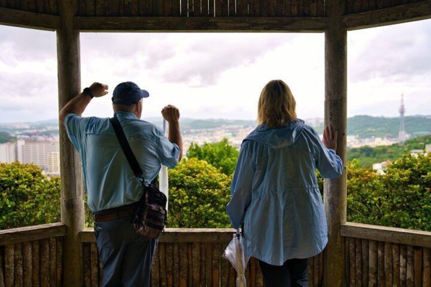 Two people standing on a wooden deck, overlooking a cityscape with a tower in the distance. 4