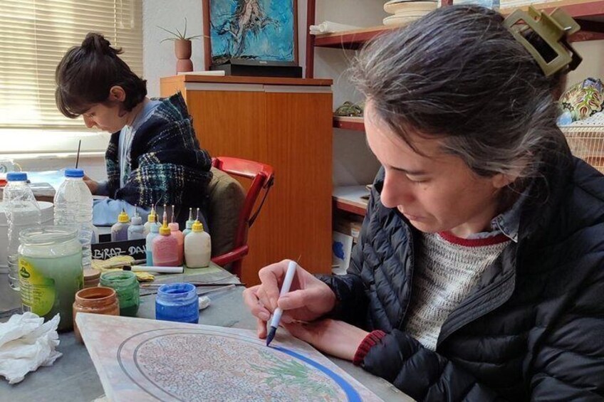 A person drawing on a paper with markers, surrounded by art supplies. 1