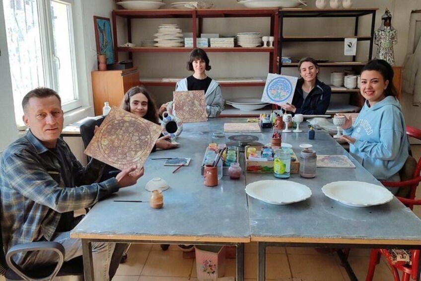 A group of people sitting around a table with pottery and ceramics. 3