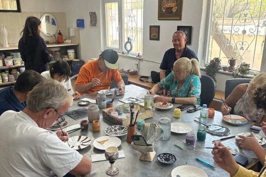 A group of people engaged in a pottery-making activity around a table with various pottery tools and materials. 2