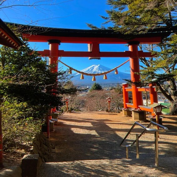 A shrine with a red torii gate, a rope bridge, and a view of a snow-capped mountain in the background. 2