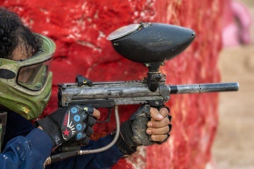 A person holding a paintball gun with a hopper and a trigger. 5