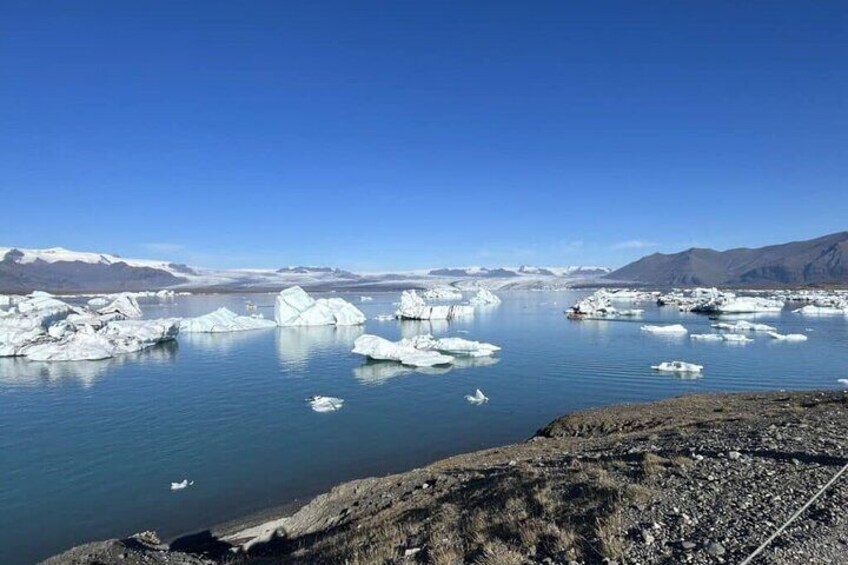 A glacier with floating icebergs in a clear blue sky. 1