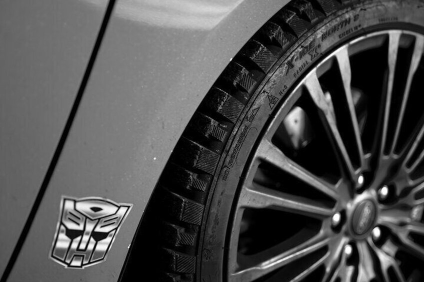 A car's side with a logo and a close-up of a wheel with a tread pattern. 4