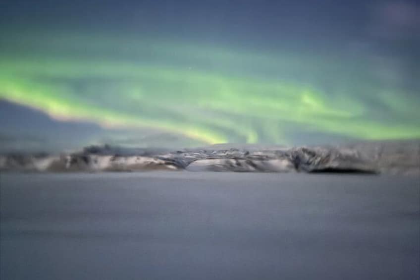 A snowy landscape with a view of the northern lights. 2