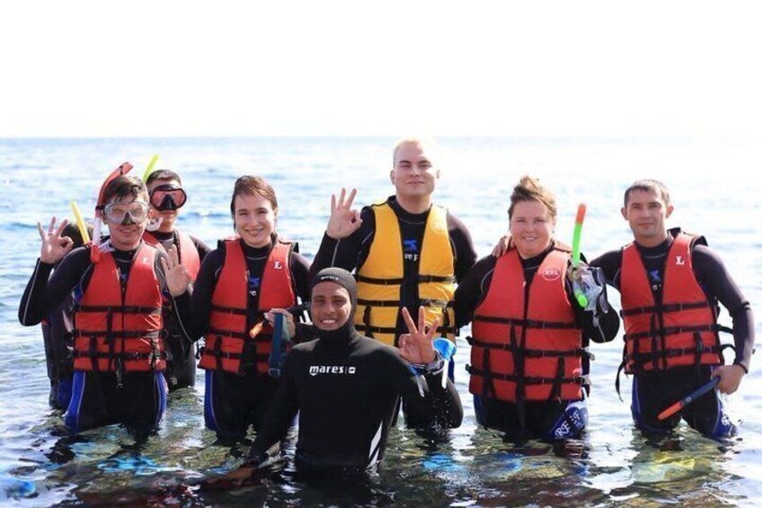 A group of people in water with life jackets, some holding snorkels. 5