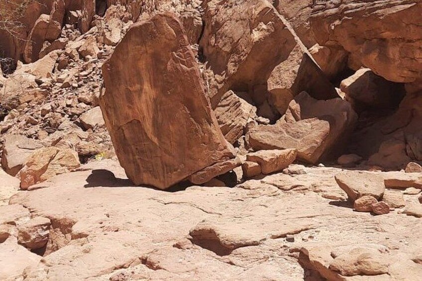 A rocky terrain with large boulders and a narrow passageway. 3