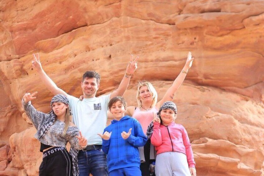 A family of five posing in front of a large rock formation. 3