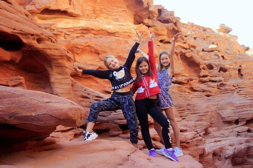 Three children posing in front of a red rock formation. 1