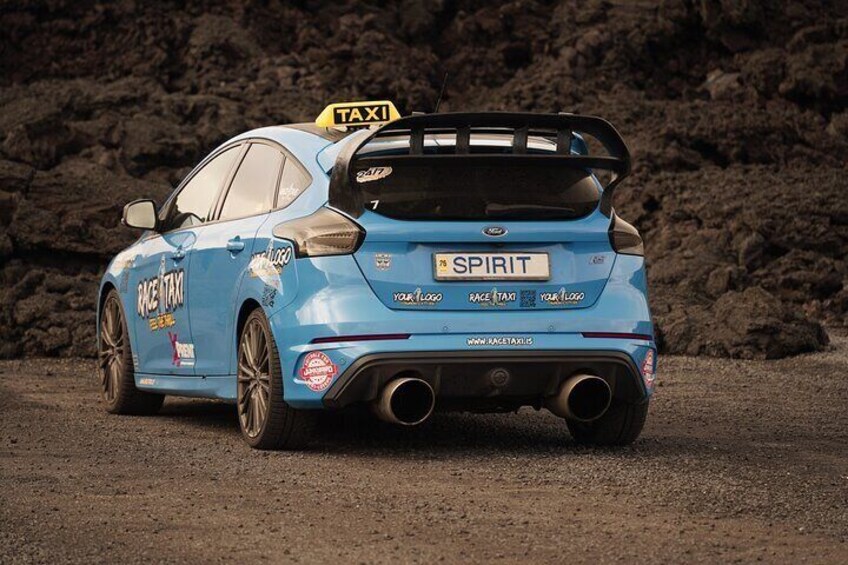 A blue rally car with 'SPIRIT' and 'TAXI' decals, a rear spoiler, and a 'TAXI' sign on the roof. 1