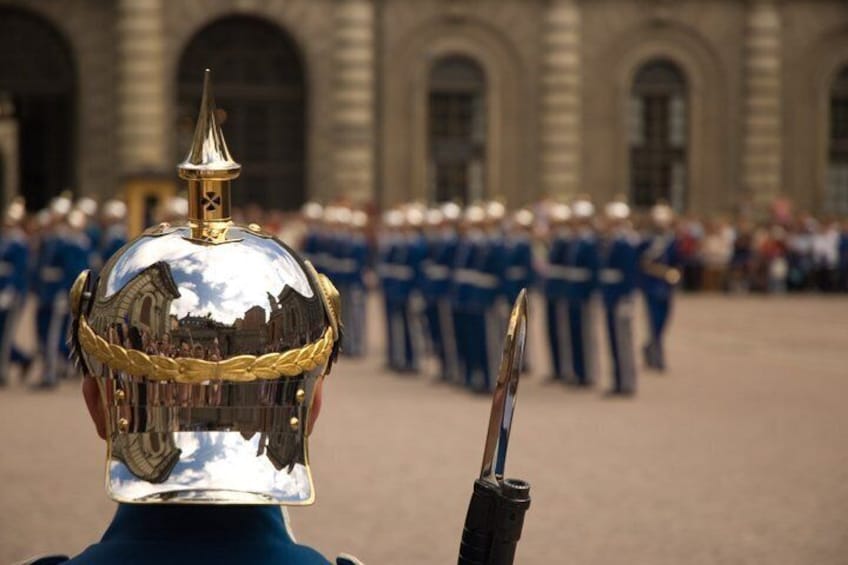 A person in a ceremonial uniform with a reflective helmet and sword, standing in front of a group of uniformed individuals in a formal setting. 3