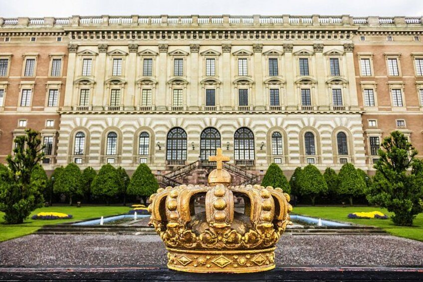 A grand building with a large golden crown statue in the foreground. 3