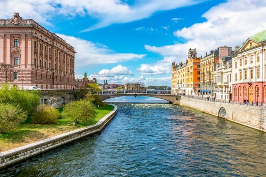 A river with buildings on both sides, a bridge in the distance, and a clear sky. 1