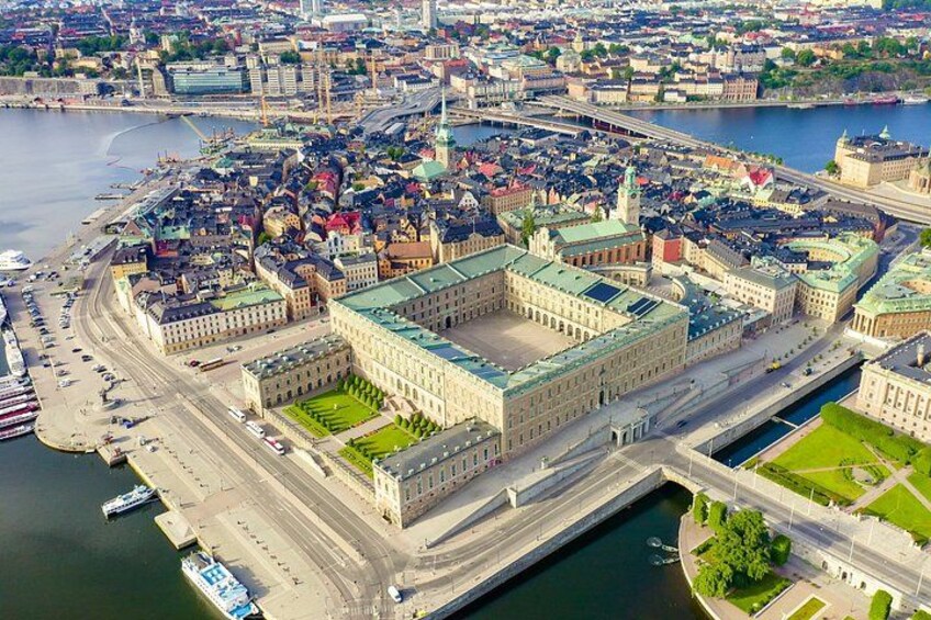 An aerial view of a city with a prominent historical building complex, a river, and a bridge. 2