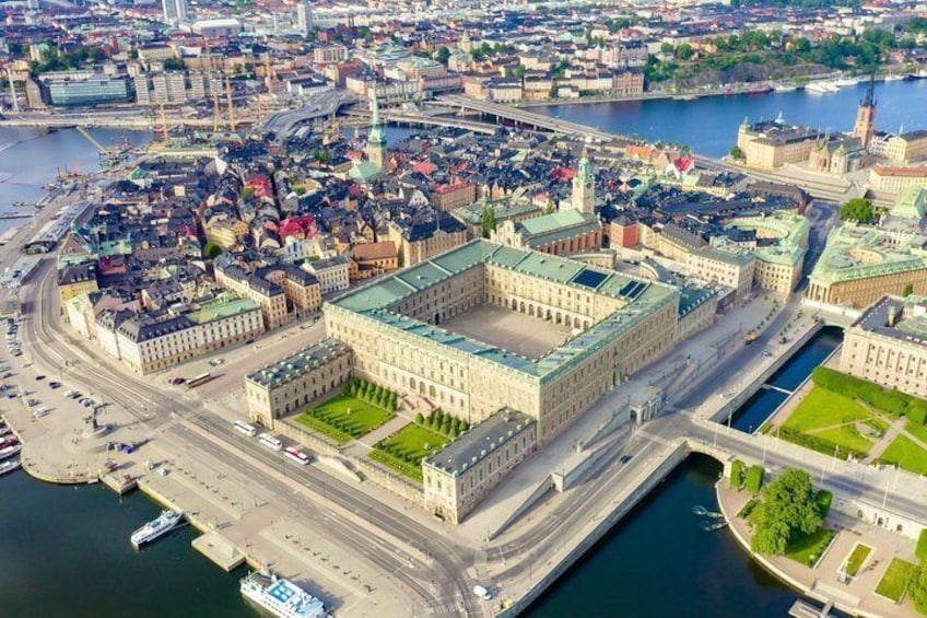 An aerial view of a historic city center with a prominent building complex, a river, and surrounding urban landscape. 1