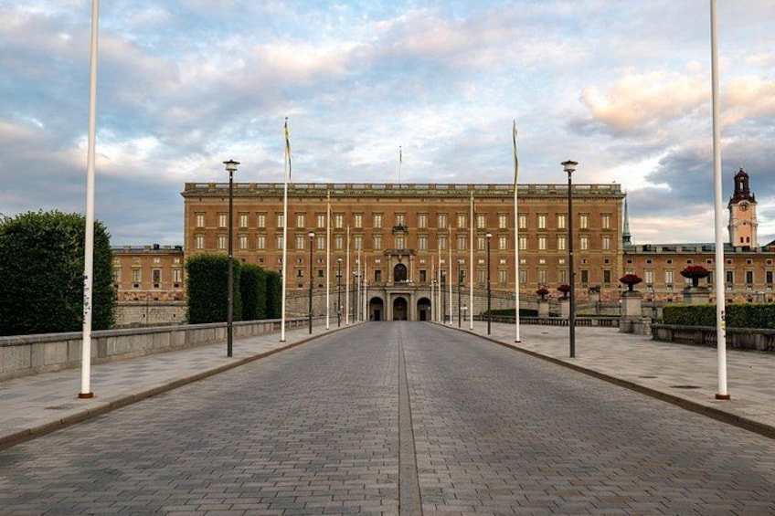 A wide paved walkway leading to a large, historic building with a clock tower. 5