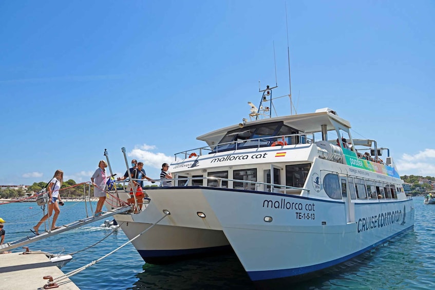 A white boat named 'Mallorca Cat' docked at a pier with people boarding and disembarking. 5