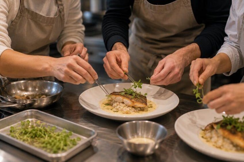 Chefs preparing a dish with fish and greens on a kitchen counter. 2