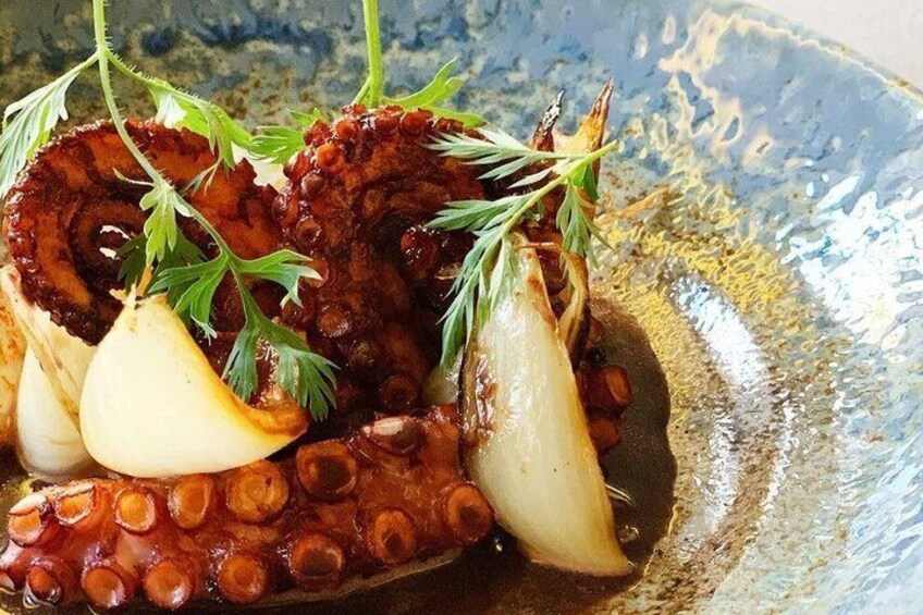 A dish of grilled octopus with lemon and herbs. 3