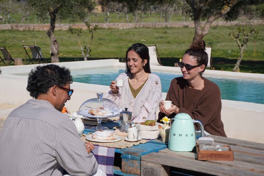 A group of people having breakfast by a poolside with a table set with food and drinks. 1