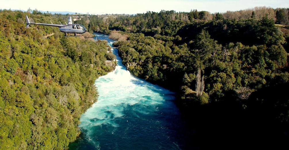 A helicopter flying over a river surrounded by dense forest. 4