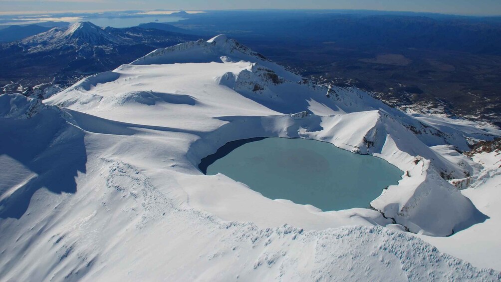 A snow-covered mountain with a small lake and distant peaks. 1