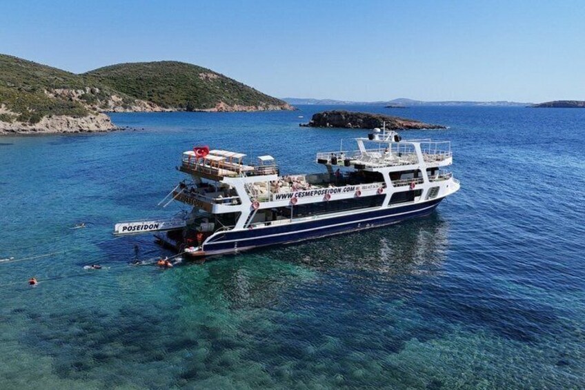 A large boat named Poseidon docked in clear blue waters with a rocky coastline in the background. 4