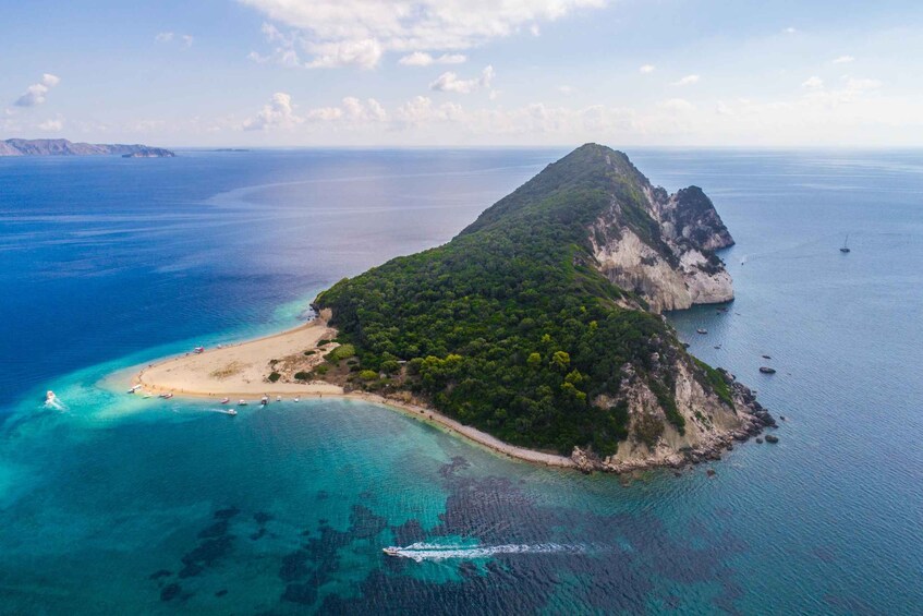 An island with a beach, clear turquoise waters, and a boat. 2