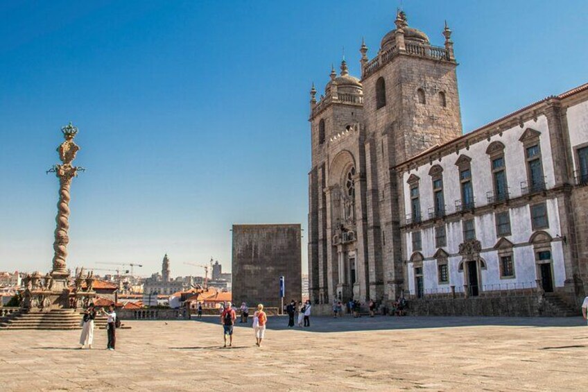 A historical building with a large tower, a fountain, and a plaza with people. 2