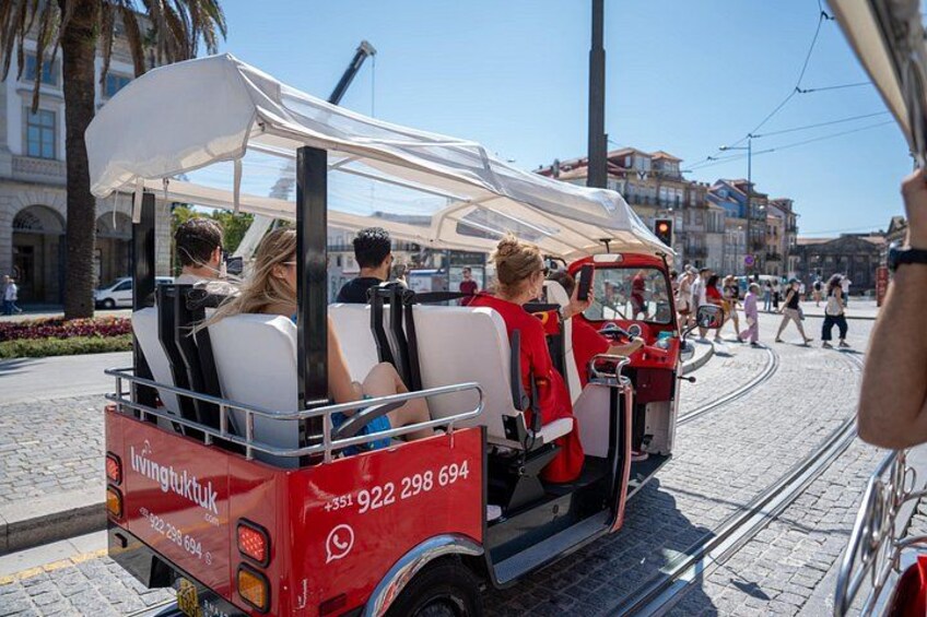 A red trolley with passengers, a white canopy, and a tram track. 2