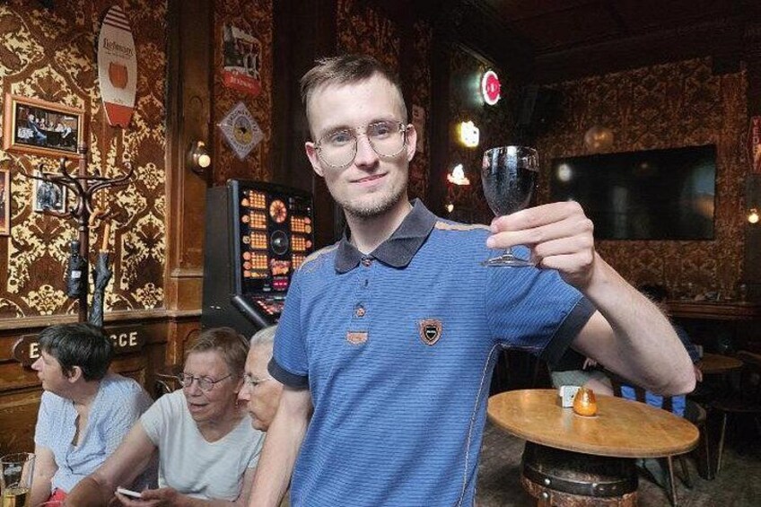 A person holding a glass in a room with patterned wallpaper and a television. 1
