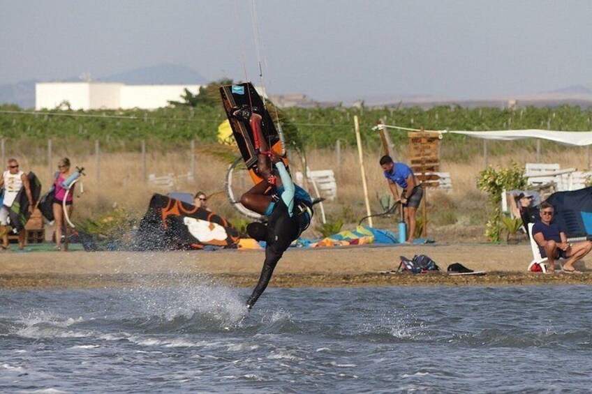 A person kiteboarding over water with onlookers in the background. 5