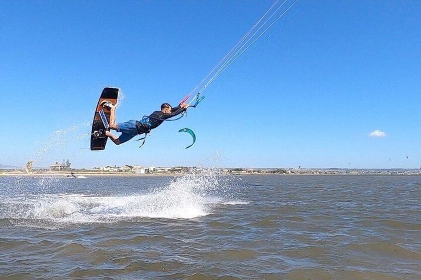 A person kiteboarding over water with a clear sky and distant buildings. 4