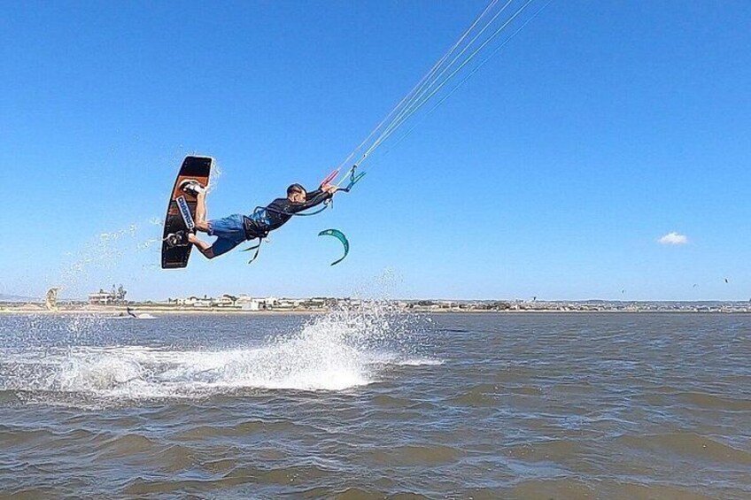 A person kiteboarding over water with a clear sky and distant shoreline. 4