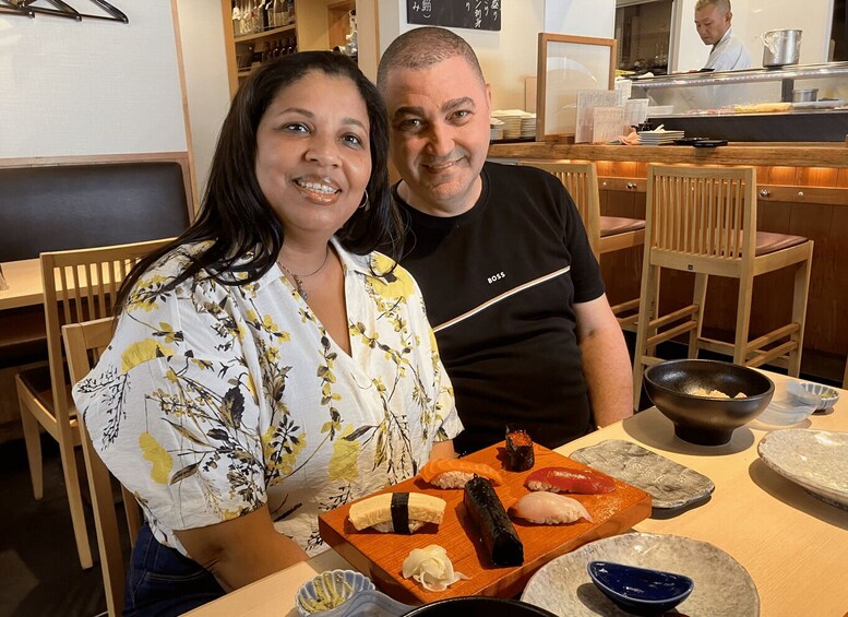A restaurant interior with wooden chairs, a sushi display, and a chef in the background. 3