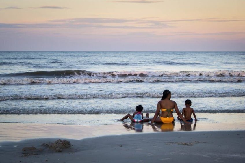 A beach with waves, a woman in a yellow swimsuit, and two children. 1