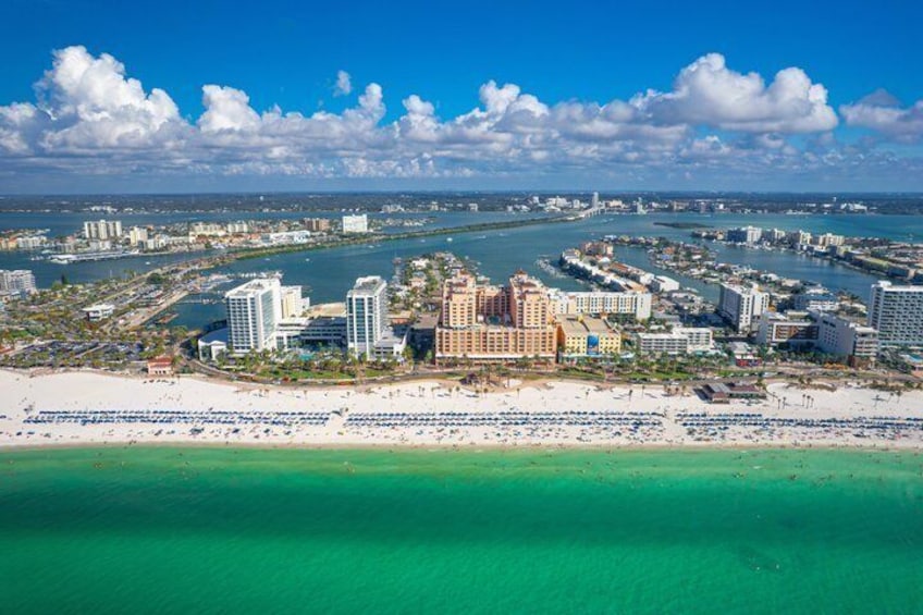 A coastal cityscape with a prominent hotel, a beach, and a marina. 3