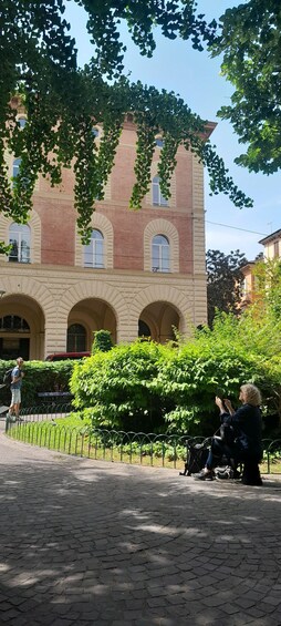 A historic building with arched windows and a brick facade, surrounded by lush greenery and a cobblestone pathway. 4