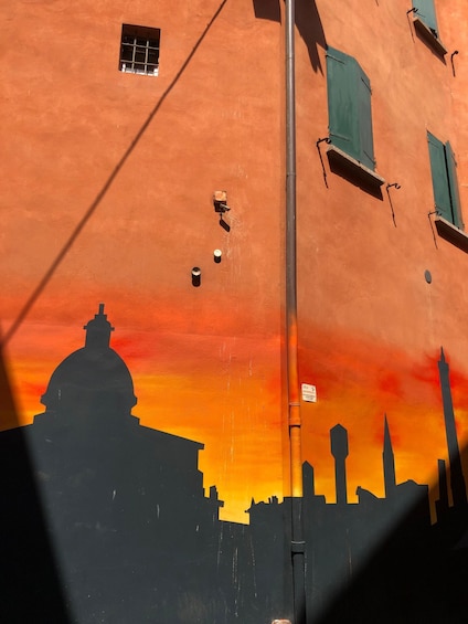 A building with a sunset silhouette mural, a streetlight, and a small window. 5