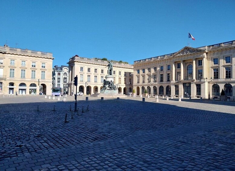 A historic square with cobblestone pavement, classical architecture, and a statue in the center. 4
