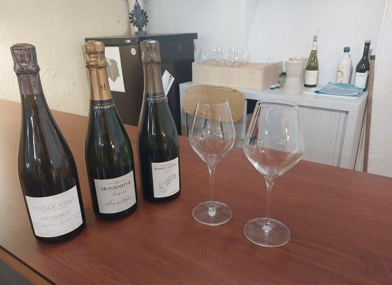 Three bottles of wine and two wine glasses on a wooden table. 3