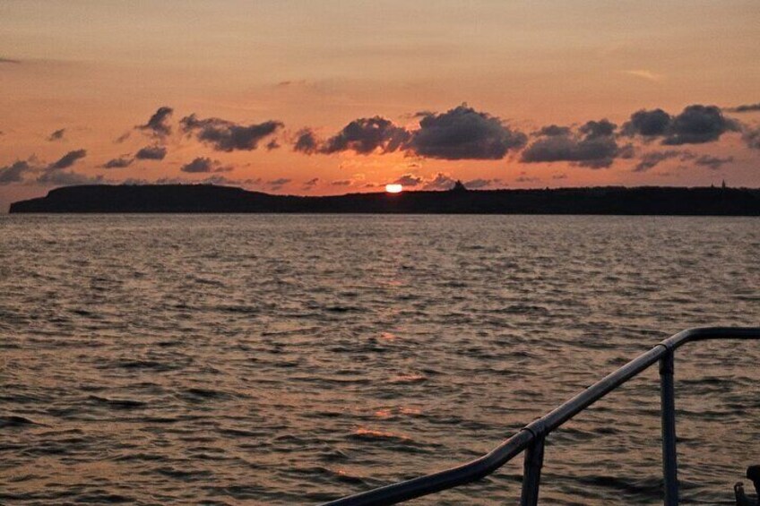 A sunset over water with a silhouette of a landmass in the distance. 4