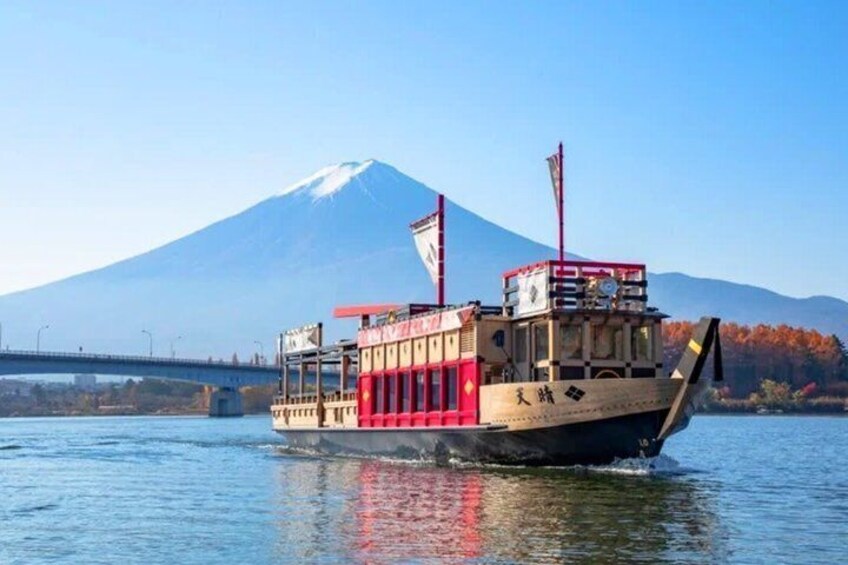 A boat with a red and beige color scheme, a flag, and a mountain in the background. 4