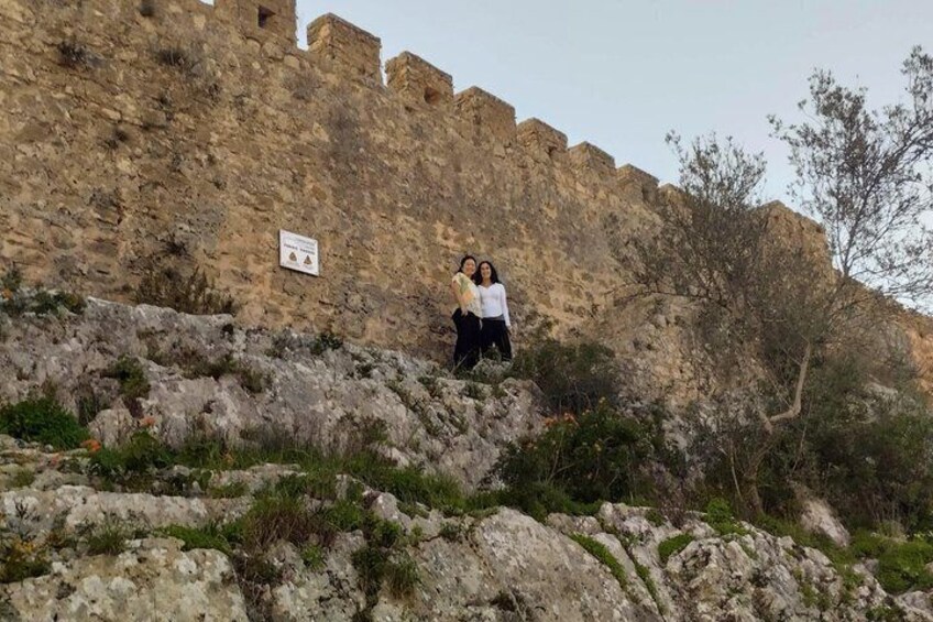 A historical stone wall with two people standing on a rocky outcrop. 3