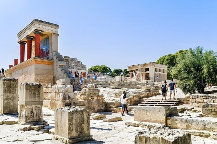 Ancient ruins with columns and steps, including a partially intact structure with a painted frieze. 1