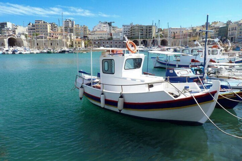 A harbor with boats docked, a clear blue sky, and buildings in the background. 5