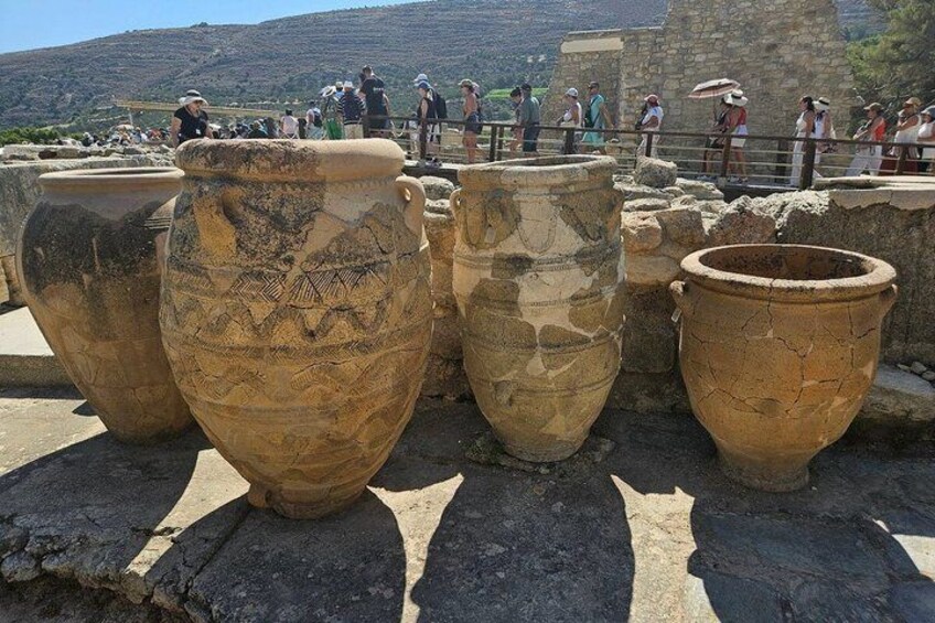 Ancient pottery on display outdoors with visitors in the background. 2