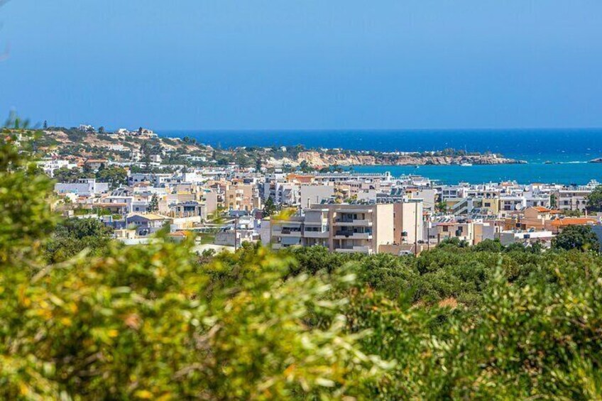 A coastal town with buildings, a clear blue sea, and a hilly landscape. 4