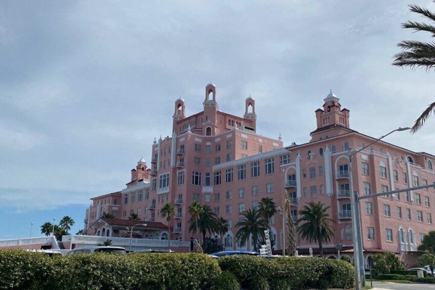 A pink, multi-story building with arched windows and a bridge in the foreground. 2