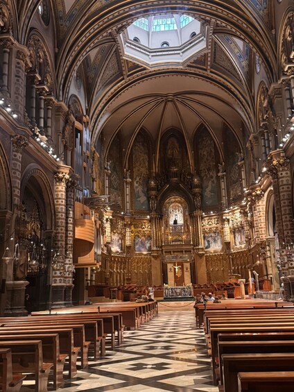 An ornate church interior with high vaulted ceilings, intricate woodwork, and a central altar. 2